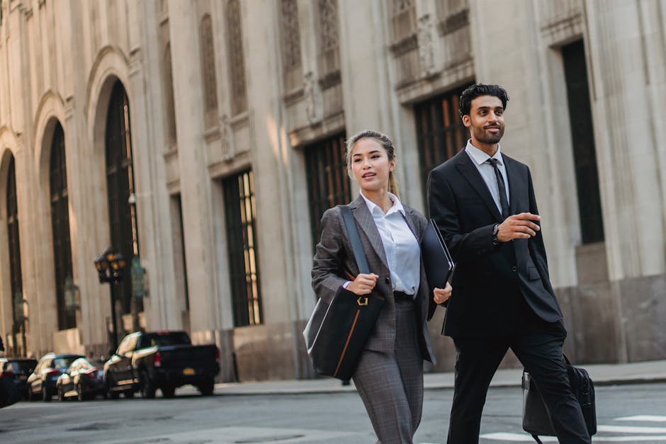 Two business professionals walking confidently on a city street, showcasing urban elegance and professional style.