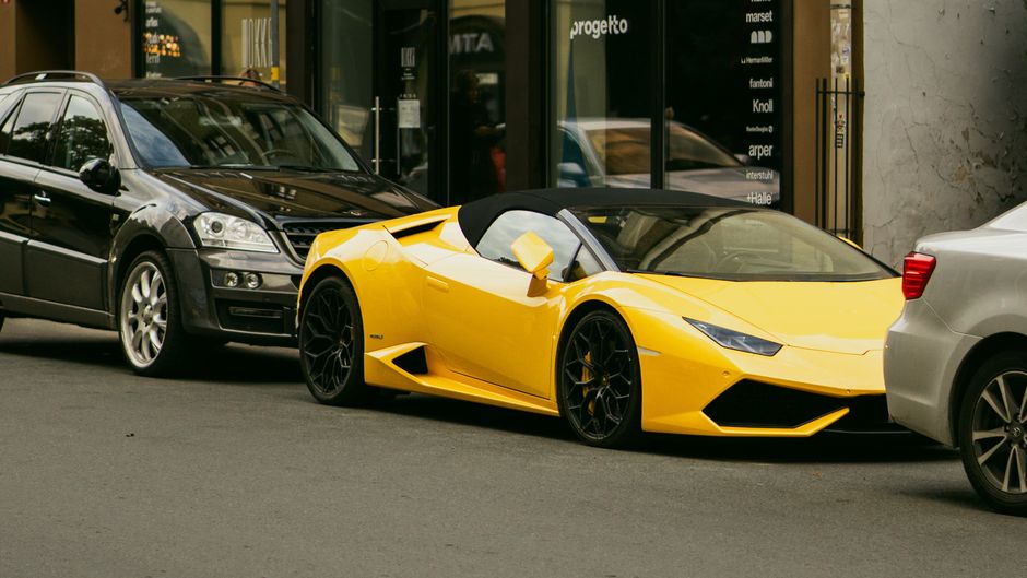 A vibrant yellow sports car parked between two other vehicles on a city street